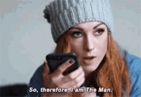 a woman wearing a beanie is holding a cell phone and says so therefore i am the man