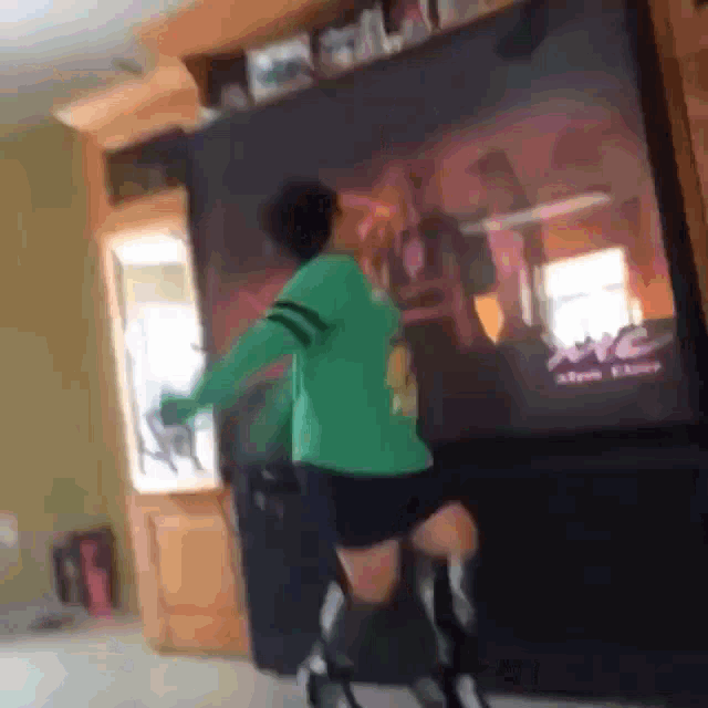 a person in a green shirt is dancing in front of a tv that says abc