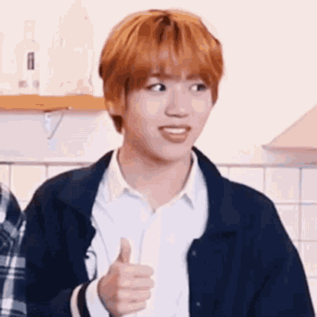 a young man with orange hair is giving a thumbs up sign .
