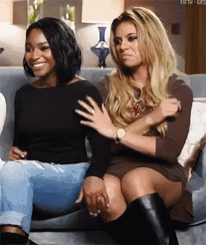 two women are sitting on a couch and one has her hand on the other 's arm