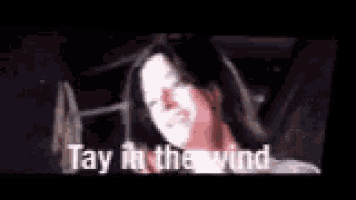 a woman is laying on a bed with her eyes closed and the words `` tay in the wink '' written on the screen .