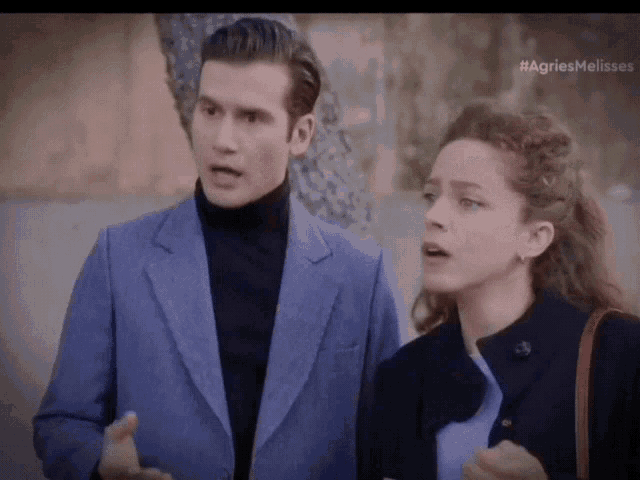 a man in a blue suit and a woman in a black coat are standing next to each other in a scene from agriesmelo