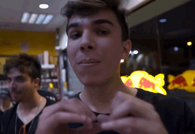 a man in front of a red bull sign looks at something