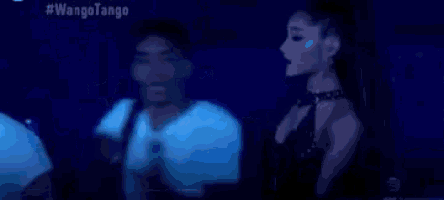 a man and a woman are dancing in front of a microphone in a dark room .