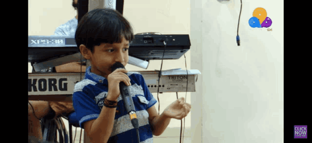 a young boy is singing into a korg microphone