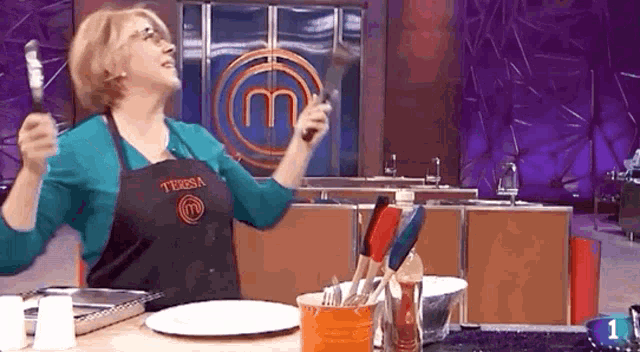 a woman wearing an apron that says teresa is holding a spatula