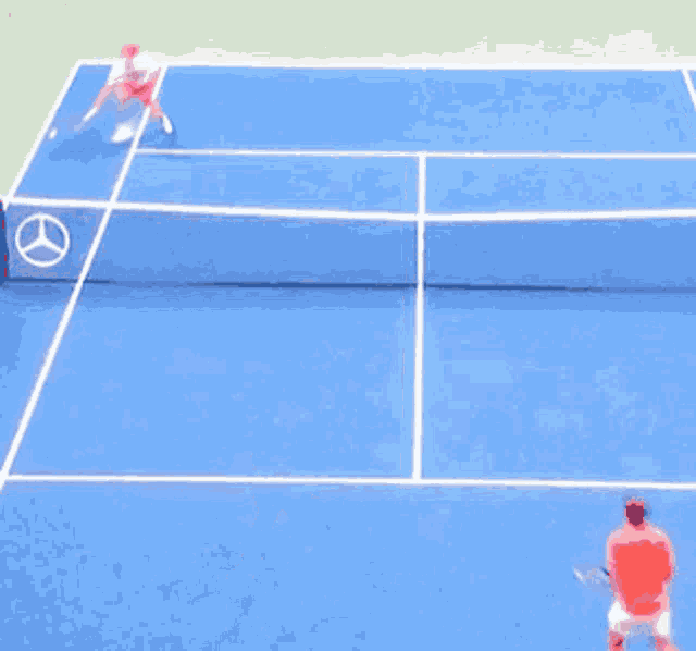 two men are playing tennis on a blue court