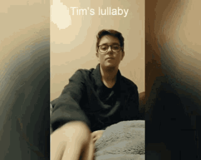 a young man wearing glasses is playing tim 's lullaby on a bed