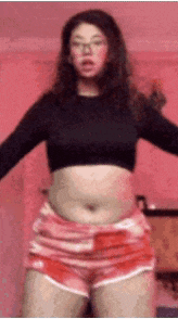 a woman in a crop top and shorts is dancing .