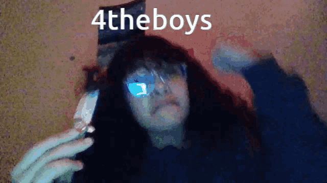 a woman wearing glasses is holding a cell phone with the words 4theboys written on the bottom