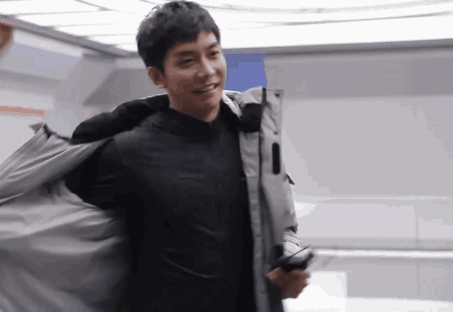 a man in a black jacket is smiling and holding a cellphone
