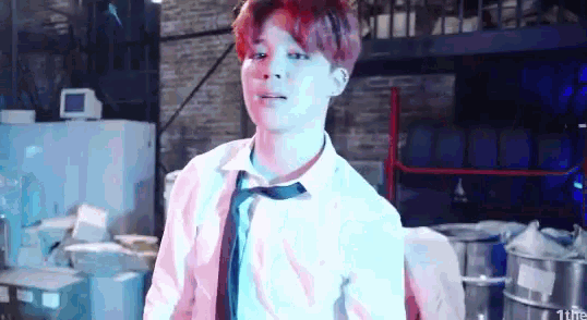 a man with red hair and a white shirt and tie is standing in a warehouse .