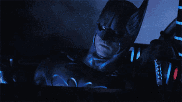 a man in a batman costume is holding a microphone in his hand