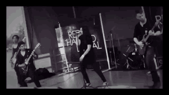 a black and white photo of a group of people playing instruments in front of a sign that says " rebel "