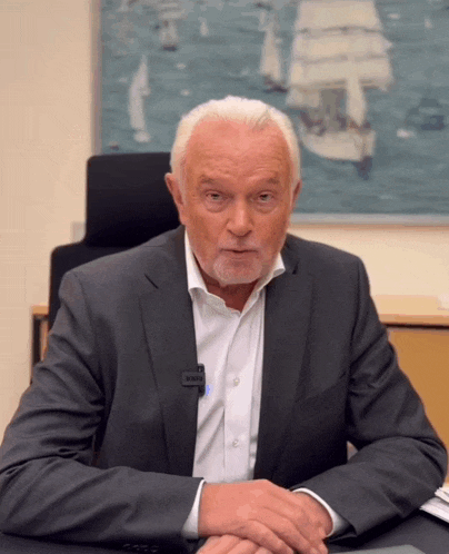 a man sitting at a desk with a microphone attached to his jacket