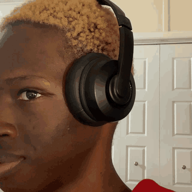 a close up of a person wearing headphones against a white door