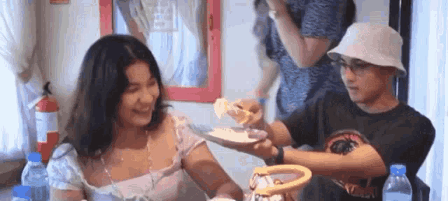 a man and a woman are sitting at a table eating food .