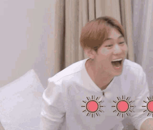a man in a white shirt is sitting on a bed with three pink suns behind him