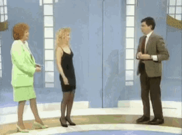 a man in a suit and tie talks to two women