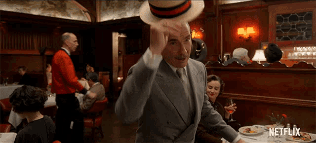 a man in a suit throws a hat in a restaurant with a netflix logo on the bottom