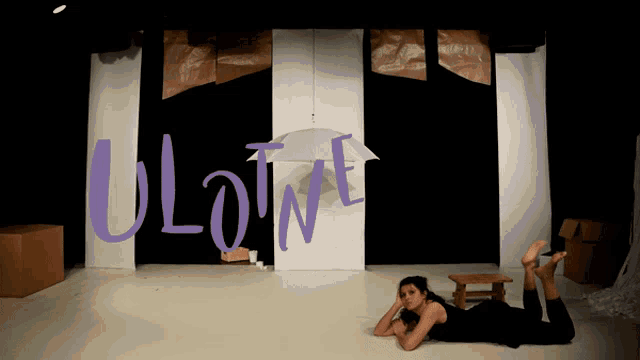a woman is laying on the floor in front of a sign that says uloume