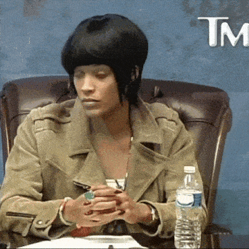 a woman sits at a table with a bottle of water and a tm logo