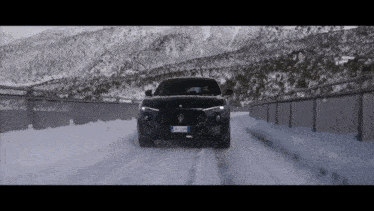 a black maserati is driving on a snowy road with a license plate that says bx jzwn
