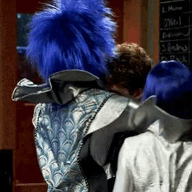 a person with blue hair is standing in front of a chalkboard