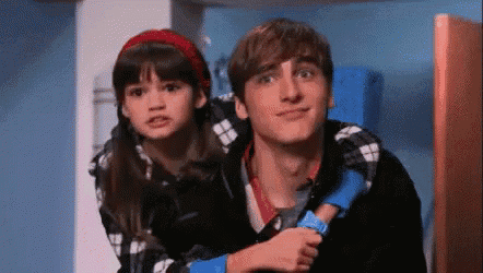 a boy and a girl are standing next to each other in a room