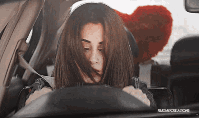 a woman driving a car with a red heart behind her