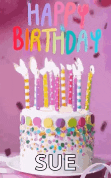 a birthday cake with candles and sprinkles on it and the name sue on it .