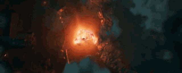 a large fireball is surrounded by clouds and a dark background