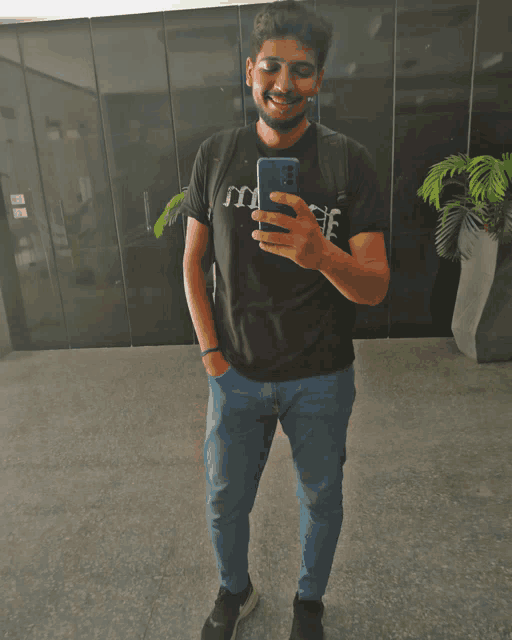 a man wearing a black shirt that says music is taking a selfie with his phone