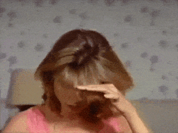 a woman in a pink shirt is holding her head in pain .