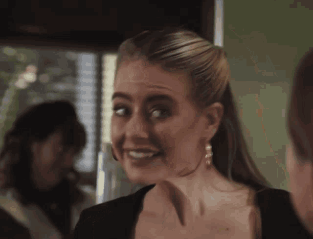 a woman wearing hoop earrings is smiling and making a face