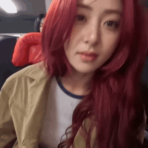 a woman with red hair is sitting on a plane and looking at the camera