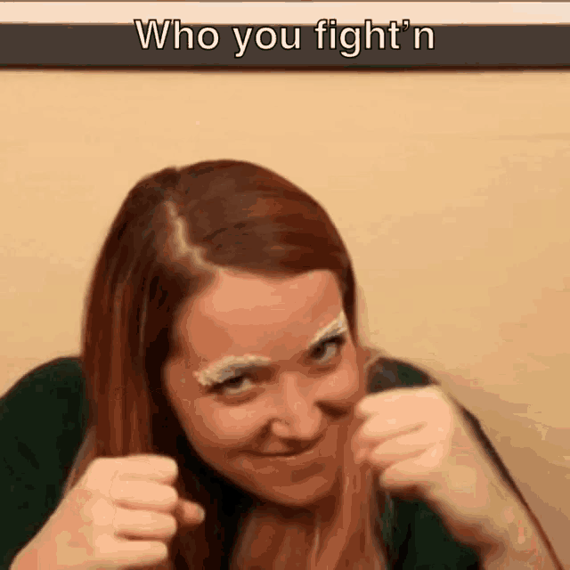 a woman with white eyebrows is making a funny face while holding her fists up in the air .