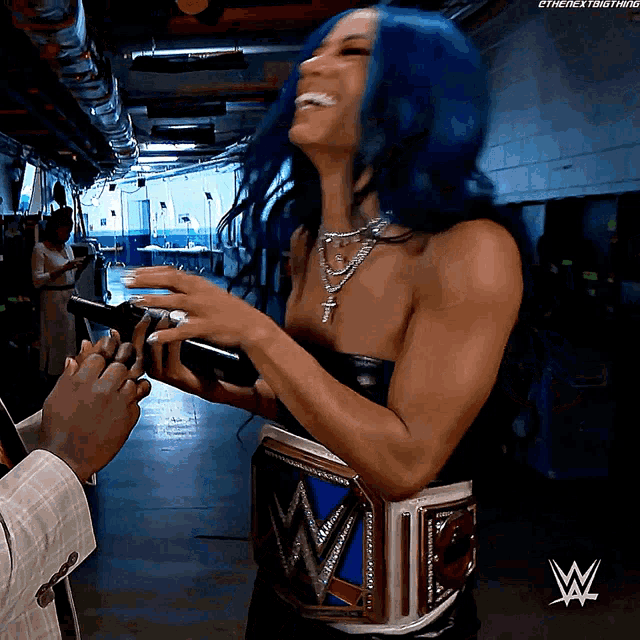 a woman with blue hair is wearing a wrestling belt with the letter w on it