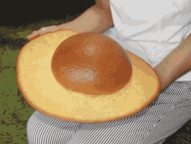 a person holding a large bread in their hands that looks like a hat