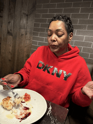 a woman wearing a red hoodie that says dkny