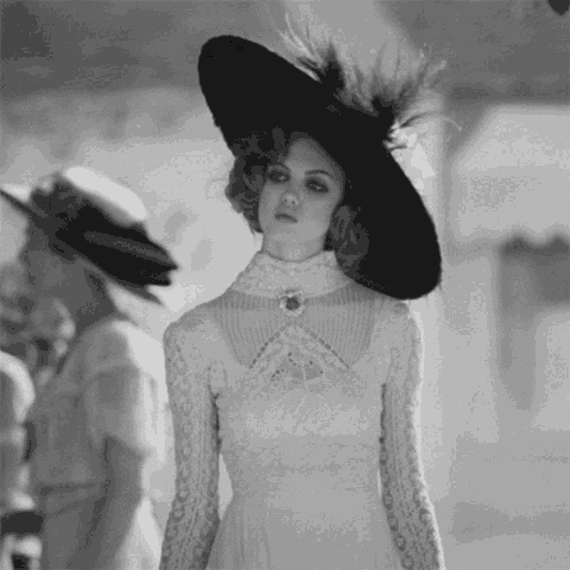 a woman in a white dress and black hat