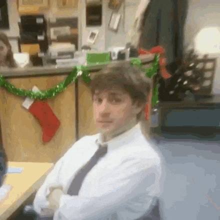 a man in a white shirt and tie is sitting at a desk in front of a christmas decoration