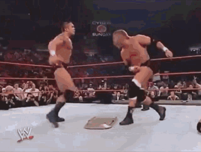 two men are wrestling in a wrestling ring with a sign that says cyber sunday in the background .