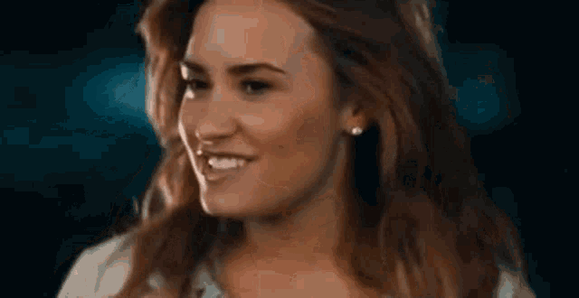 a close up of a woman 's face with long hair and earrings smiling .
