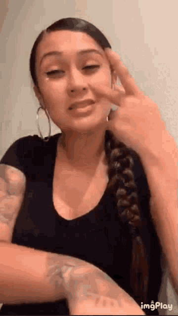 a woman with a braided hair and hoop earrings is making a funny face .