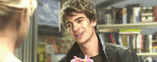 a man is holding a flower in front of a woman and smiling .
