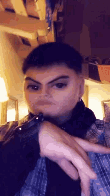 a man in a plaid shirt is making a funny face with his hand