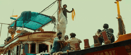 a group of people standing on top of a boat that says jai durga