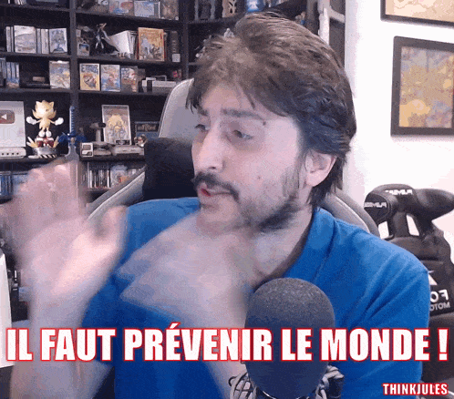 a man in front of a microphone with the words il faut prevenir le monde below him