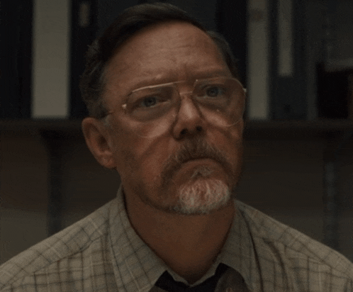 a man wearing glasses and a plaid shirt is looking up